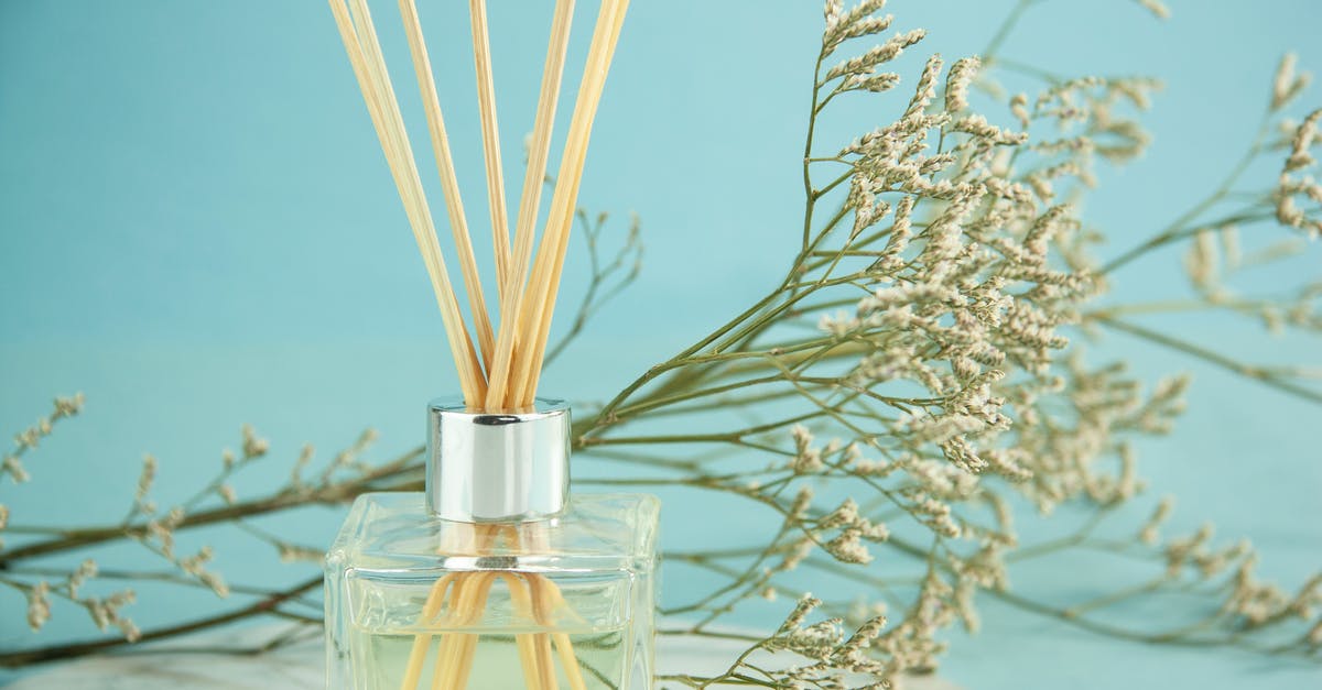 How to use herb extracts or essential oils in drinks - Composition of aroma sticks in glass diffuser with Gypsophila branches against blue background How to use herb extracts or essential oils in drinks - Composition of aroma sticks in glass diffuser with Gypsophila branches against blue background