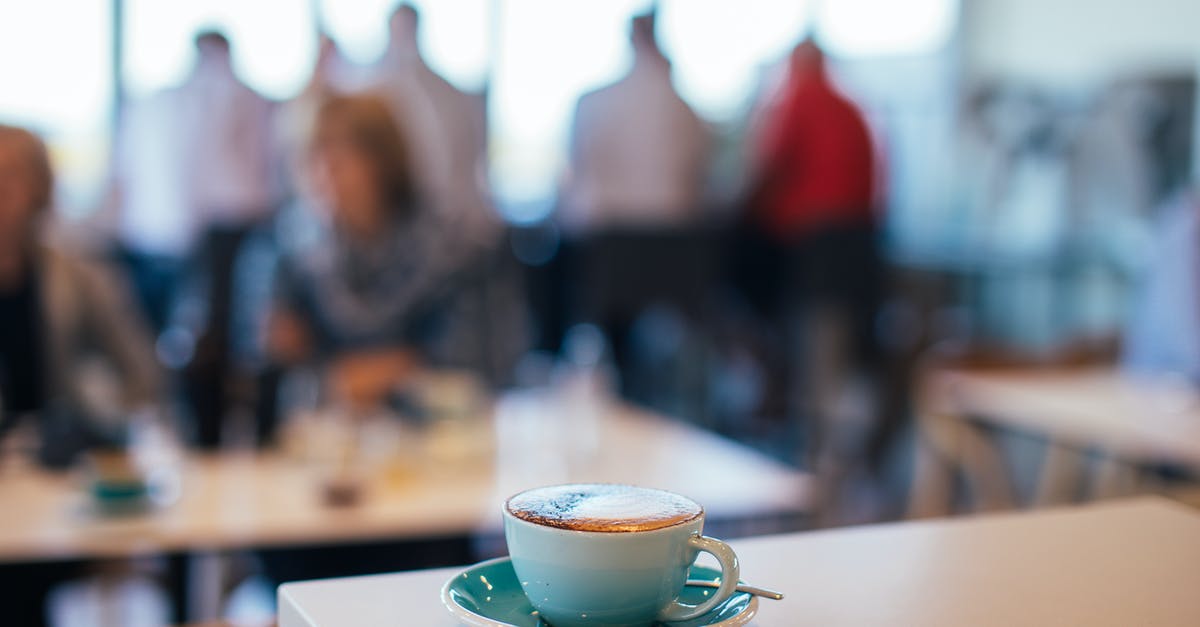 How to warm plates before serving? - Cup of tasty coffee with froth in cafe with people