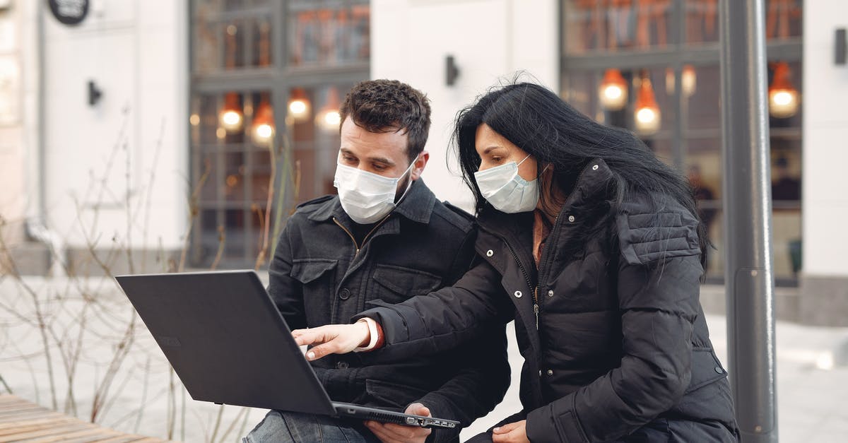 How warm must dough be in order to rise? - Focused colleagues wearing warm outerwear with protective masks on faces surfing laptop during remote teamwork sitting on wooden bench against urban building How warm must dough be in order to rise? - Focused colleagues wearing warm outerwear with protective masks on faces surfing laptop during remote teamwork sitting on wooden bench against urban building