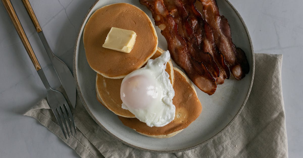 How would changing the amount of egg affect a pancake recipe? - Plate with pancakes with butter near roasted bacon and poached egg How would changing the amount of egg affect a pancake recipe? - Plate with pancakes with butter near roasted bacon and poached egg