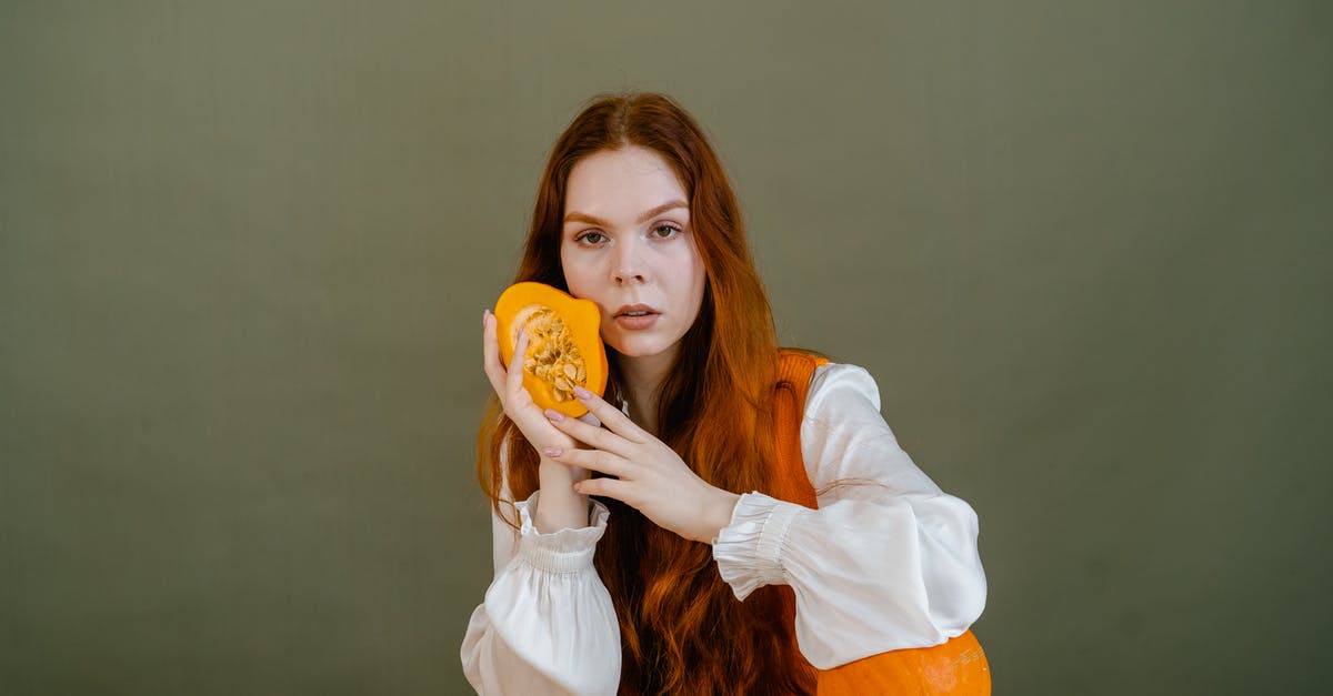 I boiled sliced yellow squash with ravioli, and it turned bluish-green -- why? - Woman in White Long Sleeve Shirt Holding Orange Vegetable
