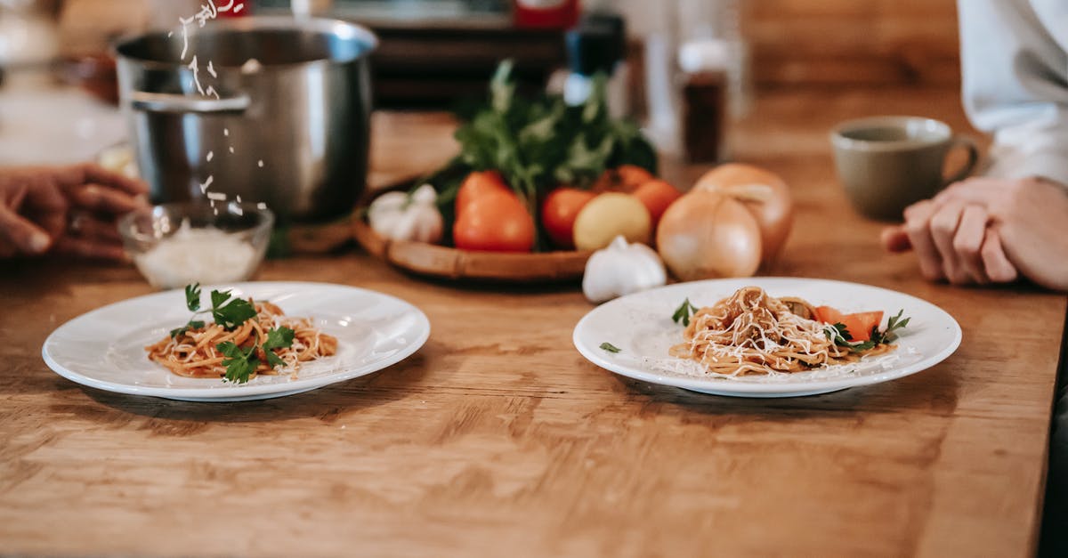 I have a recipe for an asparagus/pasta dish with a goat cheese sauce, Can I substitute Feta? - High angle of crop anonymous woman sitting at table near husband adding grated cheese on appetizing homemade spaghetti
