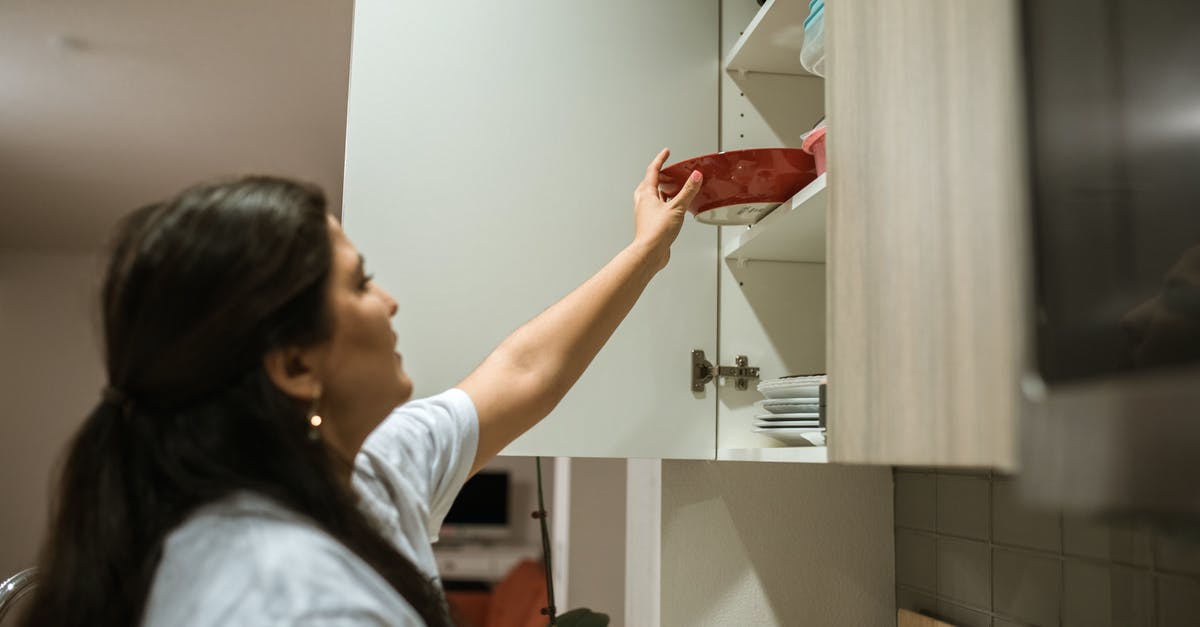 I put my cheddar in my kitchen cabinet - A Woman Putting a Plate Inside the Hanging Cabinet I put my cheddar in my kitchen cabinet - A Woman Putting a Plate Inside the Hanging Cabinet