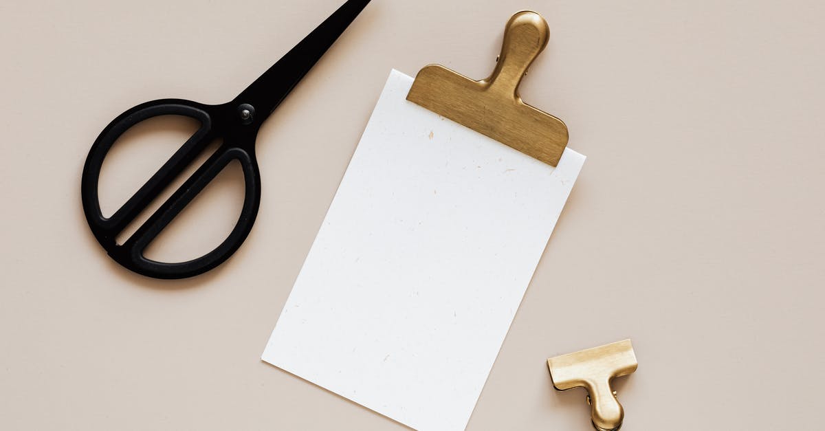I removed some of the black metallic covering of my pan, is it still safe to use? [duplicate] - Top view of smal paper clip placed on beige surface near clipboard with gold clip and modern black scissors