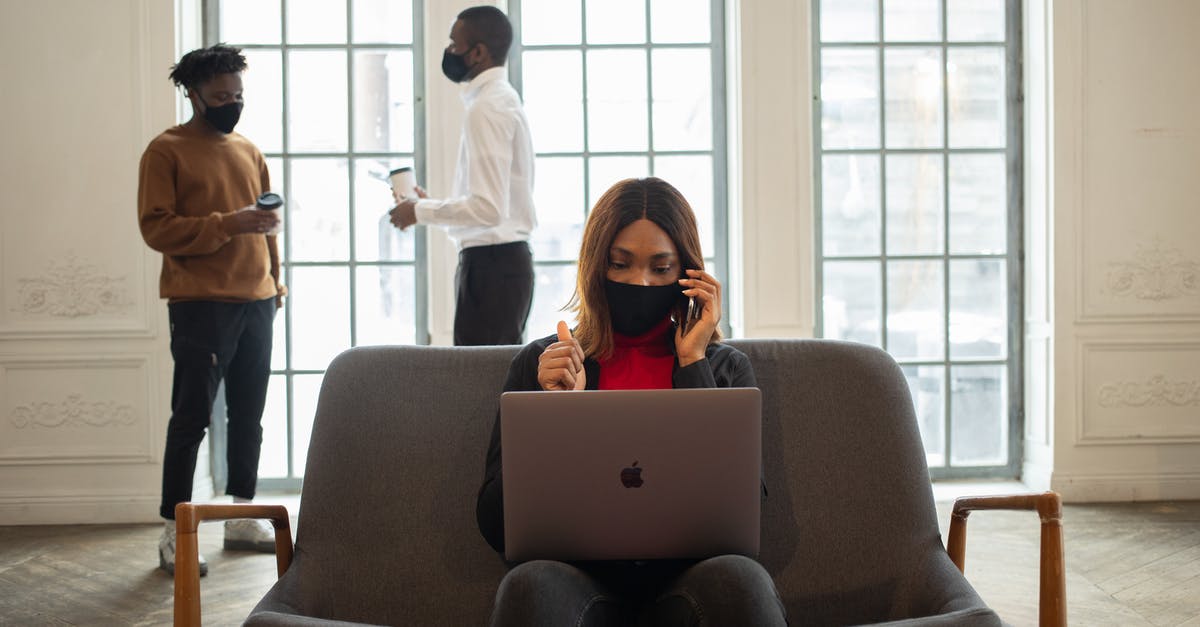 I would really like to go to bed, but the slow cooker isn't done - Ethnic female worker in fabric mask with netbook and thumb up speaking on cellphone against male partners with takeaway coffee