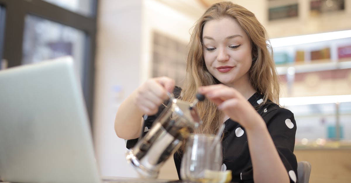 Ideal coffee grind for a French Press? - Relaxed female in trendy polka dot dress pouring hot beverage from french press into glass mug while chilling in cafe during weekend Ideal coffee grind for a French Press? - Relaxed female in trendy polka dot dress pouring hot beverage from french press into glass mug while chilling in cafe during weekend