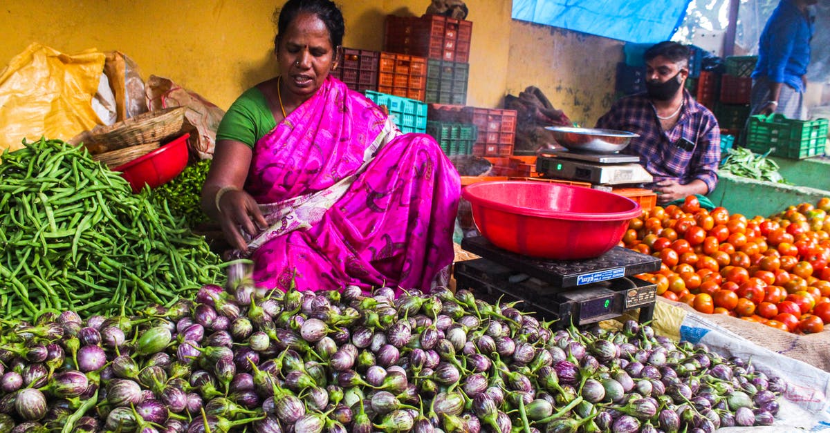 Identifying quality fruits/vegetables at a farmers market - Woman Sitting Near the Vegetables Identifying quality fruits/vegetables at a farmers market - Woman Sitting Near the Vegetables