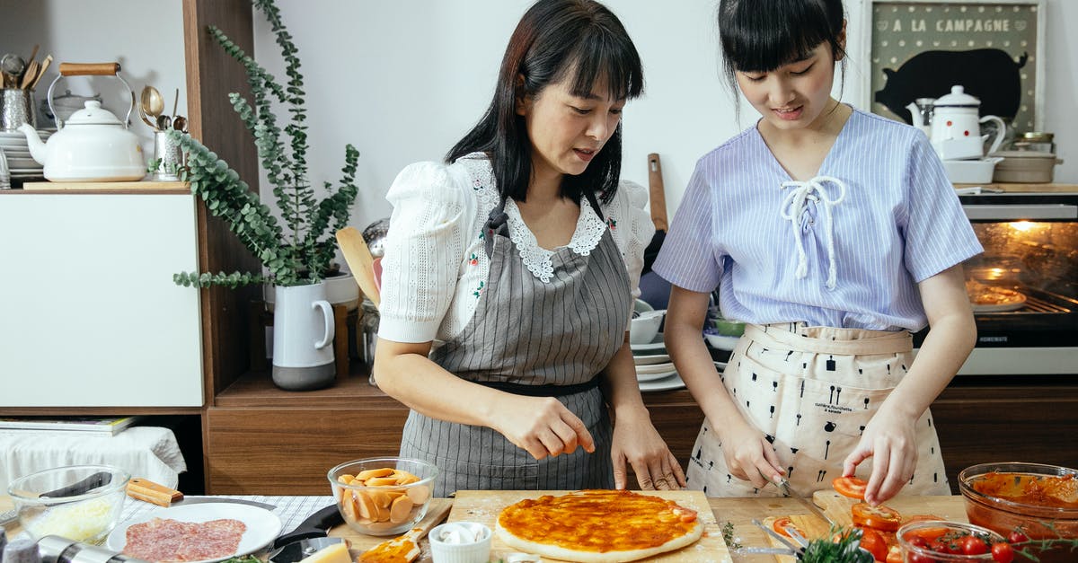 In a tomato sauce recipe, how can I cut the acidity? - Calm women cutting tomatoes on pizza In a tomato sauce recipe, how can I cut the acidity? - Calm women cutting tomatoes on pizza