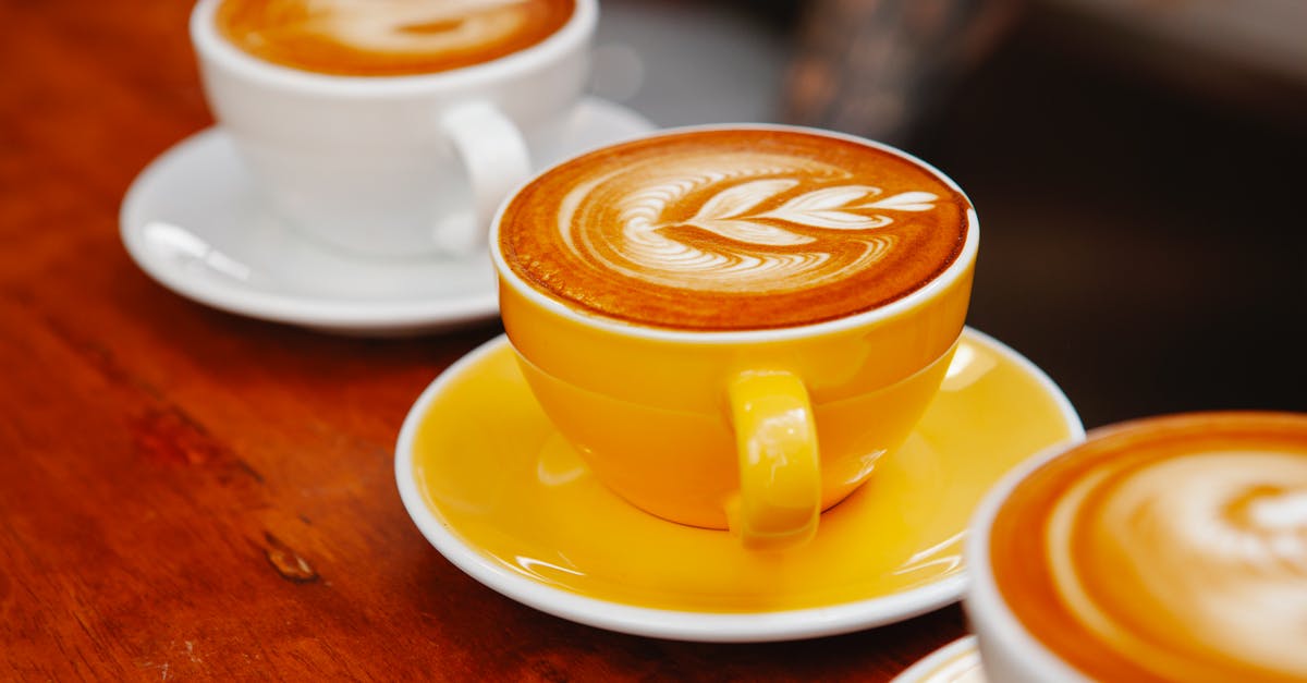 Ingredient to counter ammonia aroma/taste - Bright ceramic saucers and cups with tasty coffee with ornament on smooth froth on cafe counter Ingredient to counter ammonia aroma/taste - Bright ceramic saucers and cups with tasty coffee with ornament on smooth froth on cafe counter