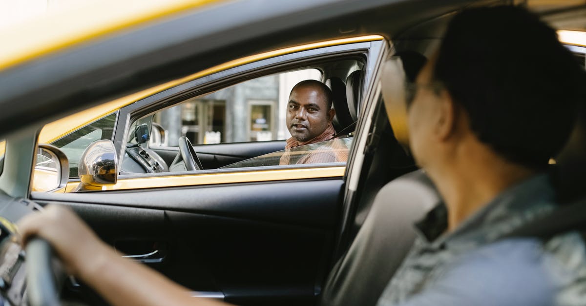 Interruption in canning process - Side view of adult ethnic male cab driver interacting with anonymous colleague driving auto while looking at each other in city Interruption in canning process - Side view of adult ethnic male cab driver interacting with anonymous colleague driving auto while looking at each other in city