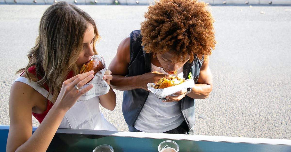 Is Beer Can Chicken safe? - Multiethnic couple biting hamburgers during lunch together Is Beer Can Chicken safe? - Multiethnic couple biting hamburgers during lunch together