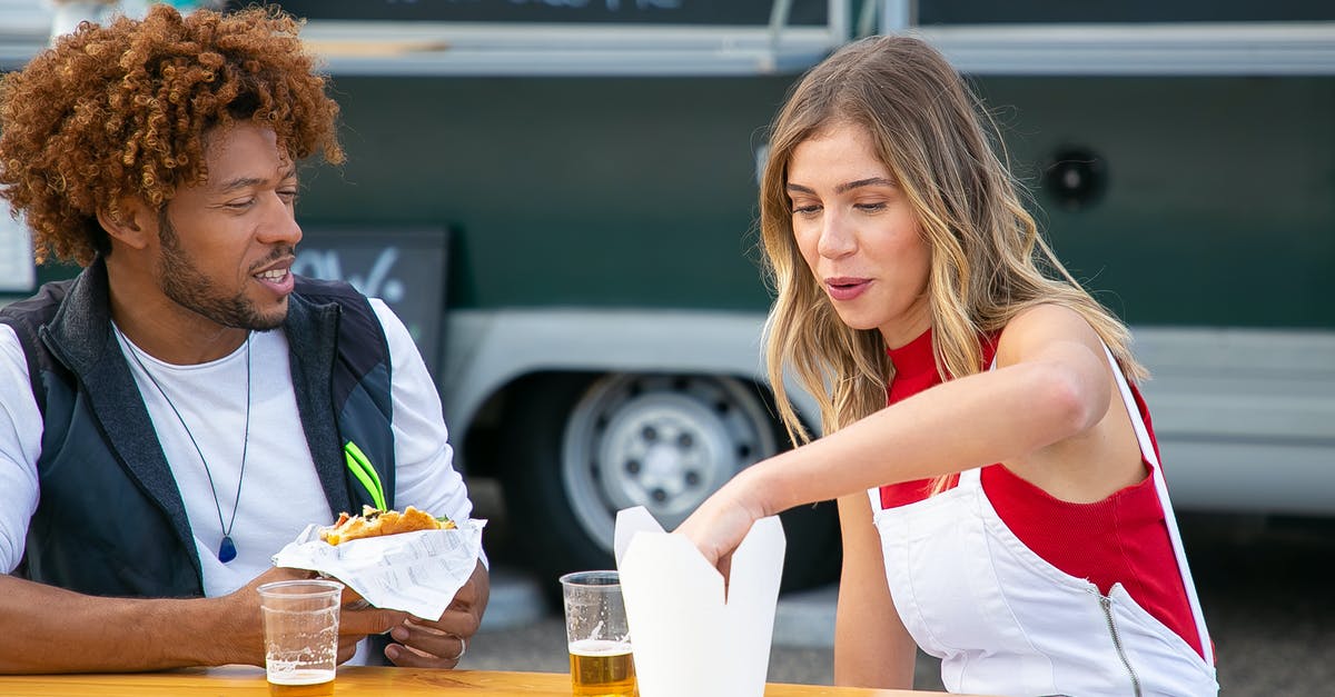 is frozen hamburger ok to eat after the sell by date? [duplicate] - Positive young female eating french fries and drink beer while sitting at table near black boyfriend with burger in hand in road cafe