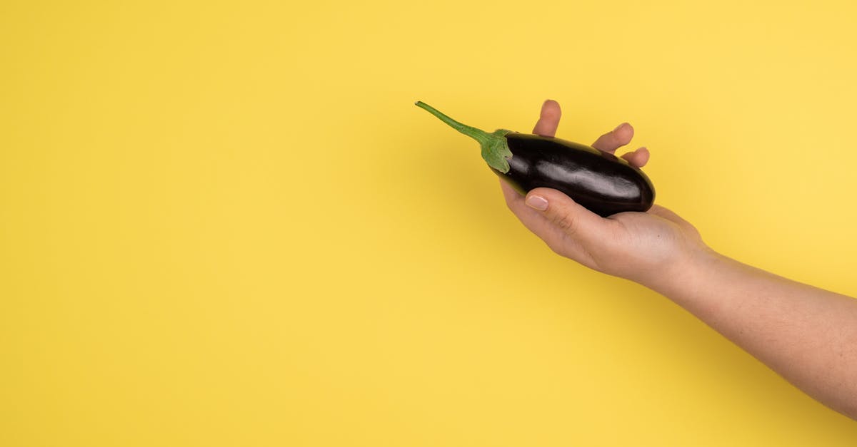 Is it necessary to peel aubergine? - Hand of crop person with eggplant Is it necessary to peel aubergine? - Hand of crop person with eggplant