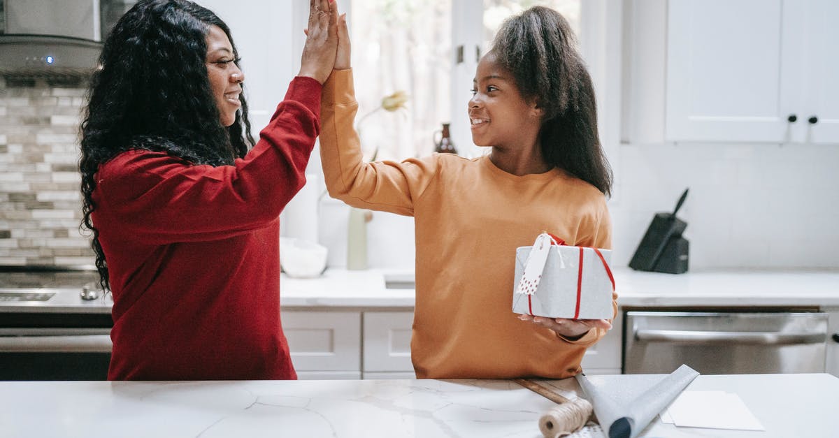 Is it safe if I use house hold scissors instead of special kitchen scissors? - Cheerful black woman and girl giving five at table and looking at each other after wrapping Christmas gift