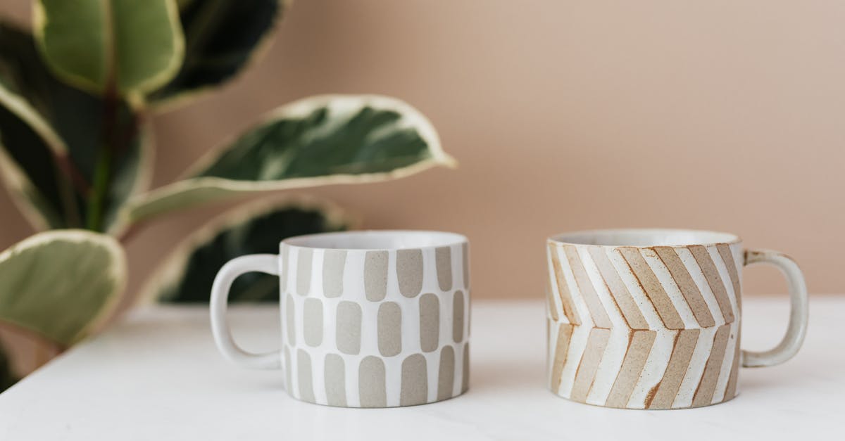 Is Pickwick green tea deceffeinated? - Handmade ceramic mugs with creative designs placed on white marble table with blurred green house plant near pink wall in background Is Pickwick green tea deceffeinated? - Handmade ceramic mugs with creative designs placed on white marble table with blurred green house plant near pink wall in background
