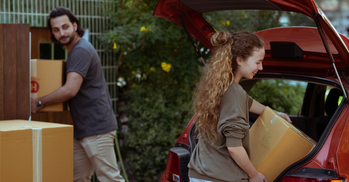 Is the grey stuff the thing we make fond out of - Couple getting carton boxes out of red car while relocating in new home