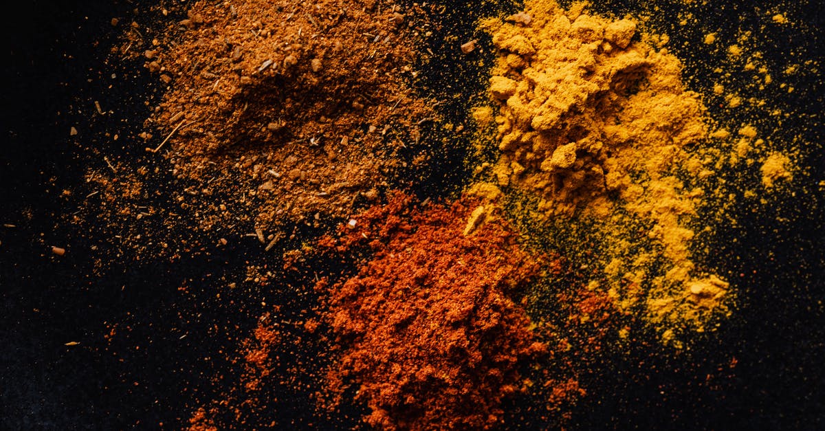 Is there a difference between seasoning and flavouring? - Assorted colorful dry powdered spices on black background Is there a difference between seasoning and flavouring? - Assorted colorful dry powdered spices on black background