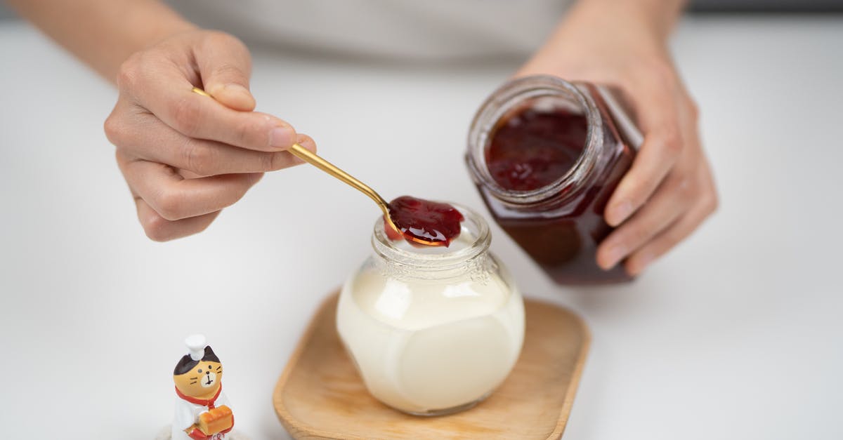Is there a milk-free sour cream? - From above crop faceless person adding berry jam to plain organic yogurt in glass jar placed on wooden saucer near tiny cat statuette Is there a milk-free sour cream? - From above crop faceless person adding berry jam to plain organic yogurt in glass jar placed on wooden saucer near tiny cat statuette