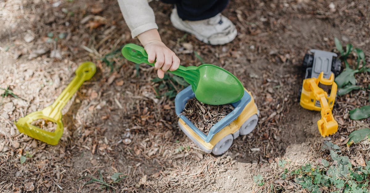 Is there a reason to have a plastic bowl? - Unrecognizable little child playing with plastic toy car and shovel in calm sunny yard Is there a reason to have a plastic bowl? - Unrecognizable little child playing with plastic toy car and shovel in calm sunny yard