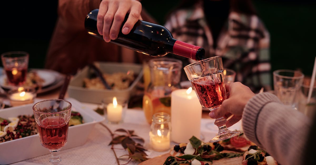 Is there a wine traditionally served with beef carpaccio? - Crop man pouring wine to people on family dinner