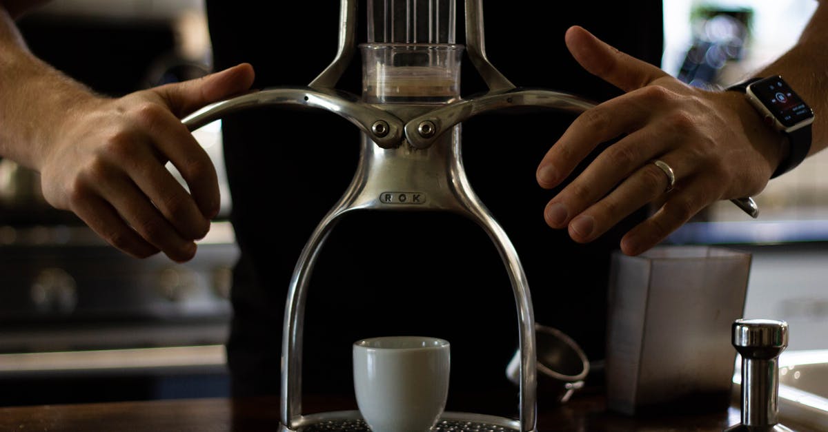 Is this coffee maker safe to use? - Crop anonymous slim male in wristwatch and golden ring using stainless steel manual drip coffee machine with ceramic cup while preparing hot drink at home