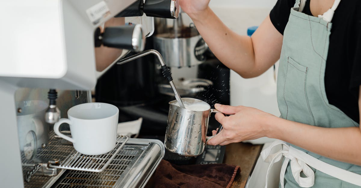 Is this coffee maker safe to use? - Crop faceless young female barista in apron steaming milk in steel pot using modern cappuccino machine
