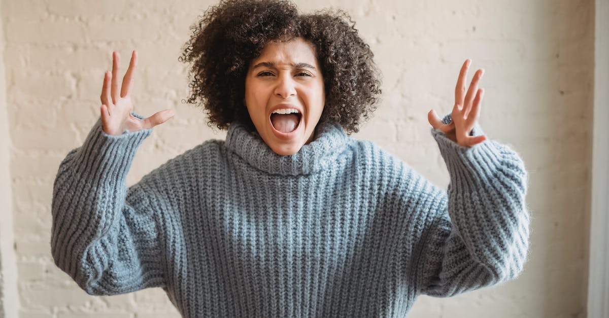Is this kind of outlook in the wall inside an opened can looking normal? - Irritated African American female with raised arms looking at camera while shouting loudly near wall in light room at home Is this kind of outlook in the wall inside an opened can looking normal? - Irritated African American female with raised arms looking at camera while shouting loudly near wall in light room at home