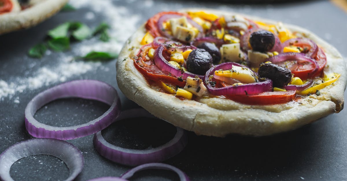 Jalapeno Poppers and getting a thick crust? - Cut pizza with olive and corn on thick dough served on table with flour Jalapeno Poppers and getting a thick crust? - Cut pizza with olive and corn on thick dough served on table with flour
