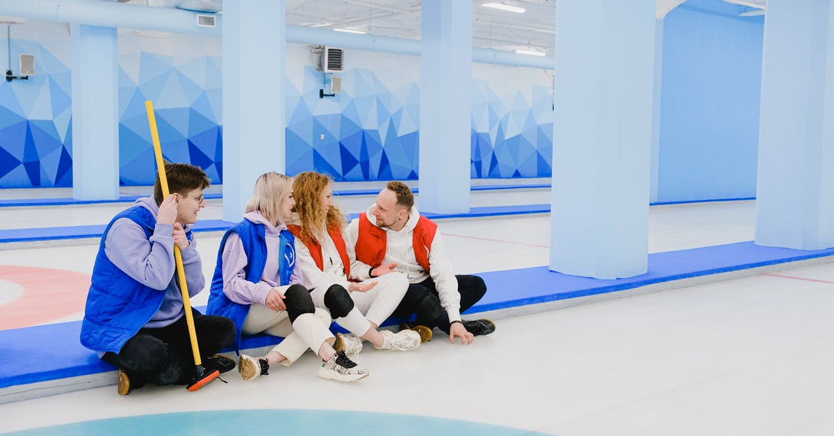 Keeping crushed ice from melting, without it joining back together - Sportsmen in red and blue waistcoats chatting on floor of spacious curling arena Keeping crushed ice from melting, without it joining back together - Sportsmen in red and blue waistcoats chatting on floor of spacious curling arena