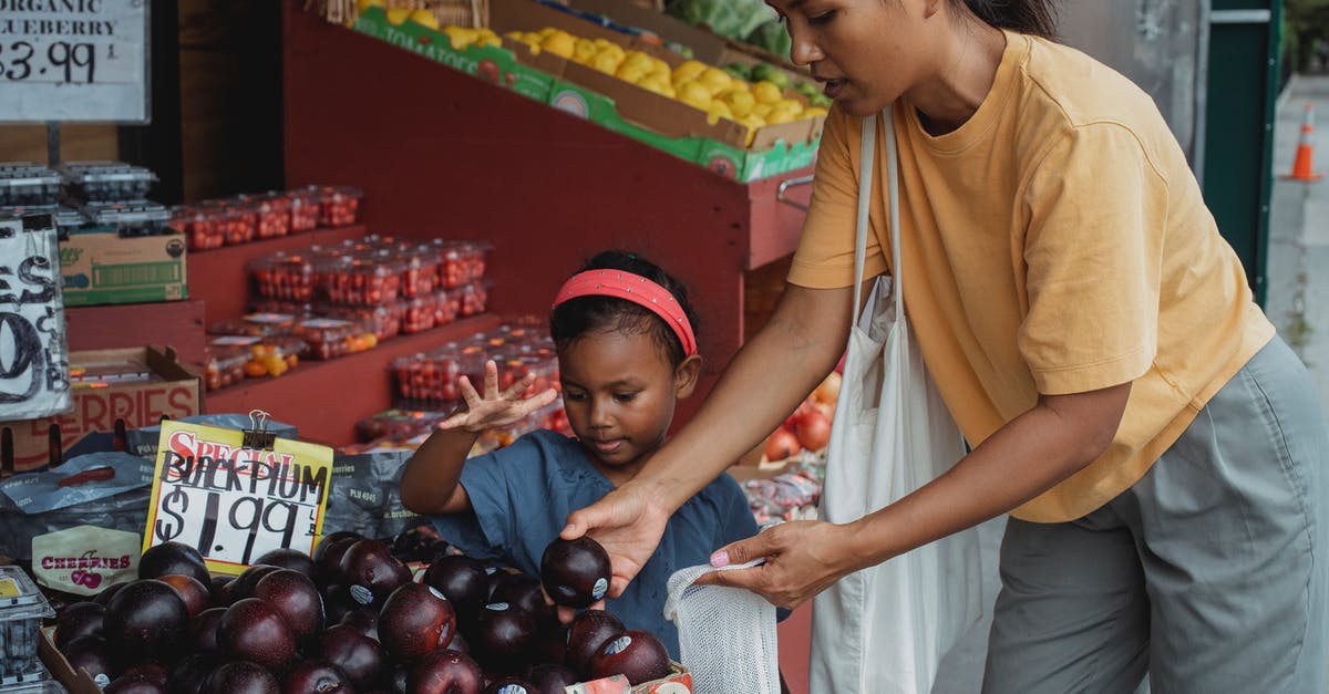 Kids Lunch box - suggestion for fruit smoothie packaging - Asian woman putting black plum into eco bag while choosing fruits from box in street market with daughter Kids Lunch box - suggestion for fruit smoothie packaging - Asian woman putting black plum into eco bag while choosing fruits from box in street market with daughter