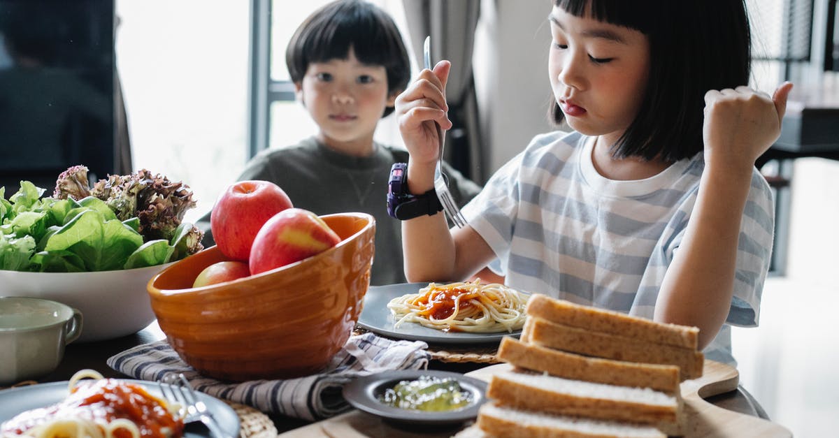 Kind of apples for apple purée / apple sauce - Serious little Asian girl eating delicious pasta with cute brother while sitting at table with healthy salad and apples on sunny day Kind of apples for apple purée / apple sauce - Serious little Asian girl eating delicious pasta with cute brother while sitting at table with healthy salad and apples on sunny day