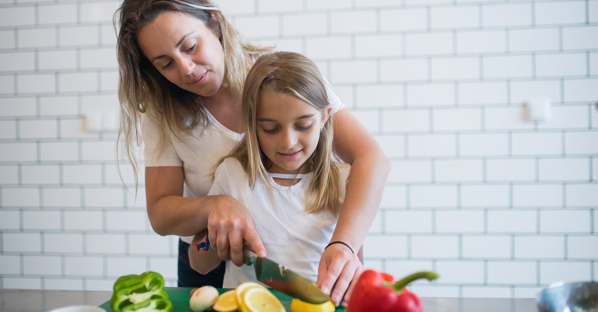 Knife chopping through bone or coconut - Girl in White Tank Top Assisting Daughter to Chop Lemon