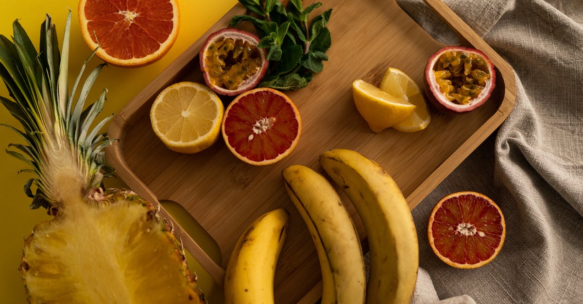 Lemon juice as a natural preservative for soups - High angle of cut pineapple and banana with halves of grapefruit and passion fruit and sliced lemon on wooden tray Lemon juice as a natural preservative for soups - High angle of cut pineapple and banana with halves of grapefruit and passion fruit and sliced lemon on wooden tray