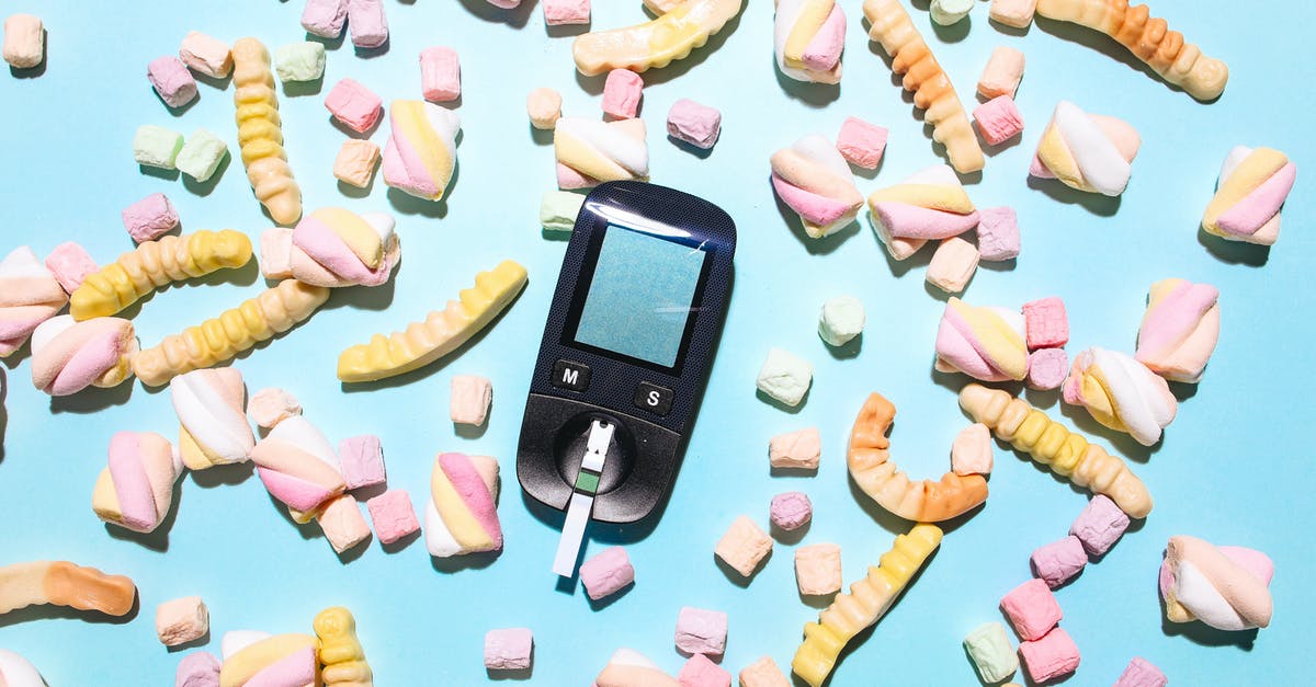 Liquid glucose in marshmallows - Glucose Meter Surrounded by Sweet Treats on a Blue Surface Liquid glucose in marshmallows - Glucose Meter Surrounded by Sweet Treats on a Blue Surface