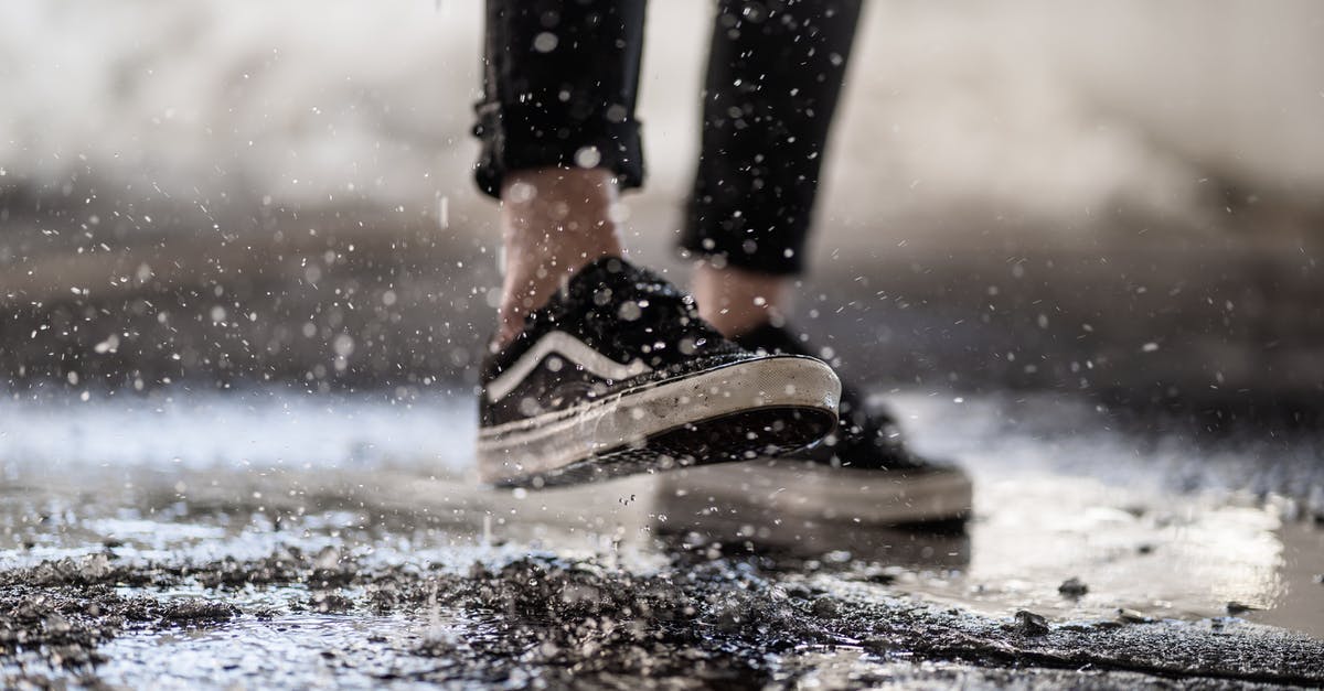 Macarons are wrinkled, cracked and have no feet - Crop person walking through puddles on asphalt Macarons are wrinkled, cracked and have no feet - Crop person walking through puddles on asphalt