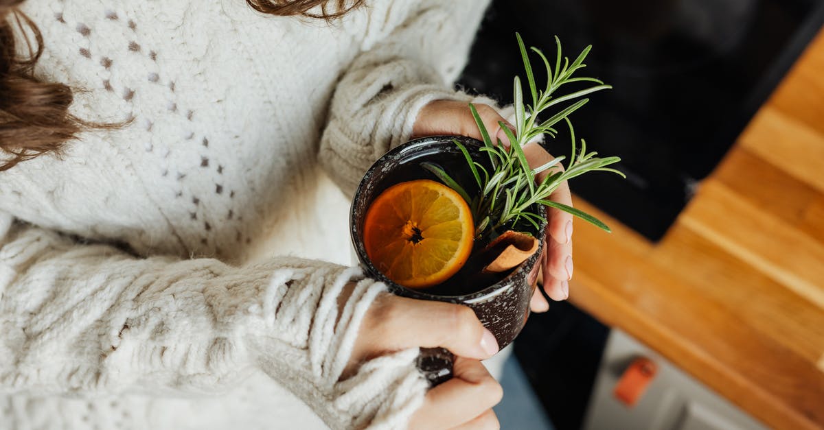 Make lemon balm tea - recommended method - Woman in White Sweater Holding Black Ceramic Mug With Orange Liquid Make lemon balm tea - recommended method - Woman in White Sweater Holding Black Ceramic Mug With Orange Liquid