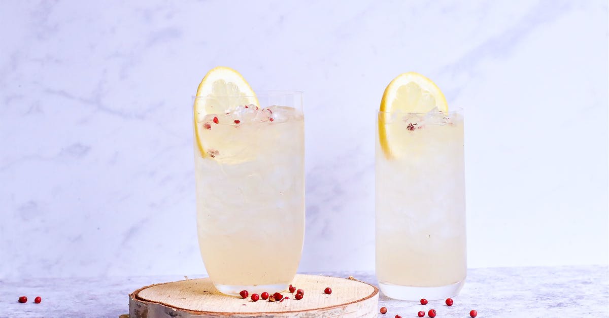 making a detox smoothie more palatable - Glasses of delicious cold lemonade decorated with lemon slice and berries on wooden board in light studio