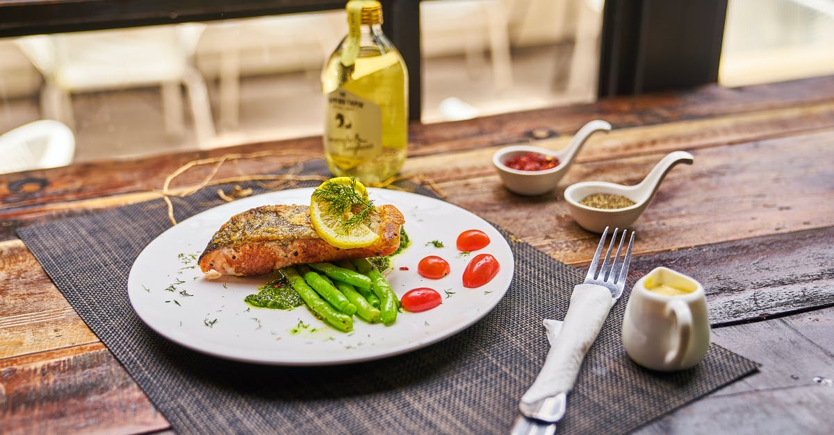 Making lemon oil from vodka - High angle of served plate with fried fish and vegetables placed near saucers with spices and olive oil Making lemon oil from vodka - High angle of served plate with fried fish and vegetables placed near saucers with spices and olive oil