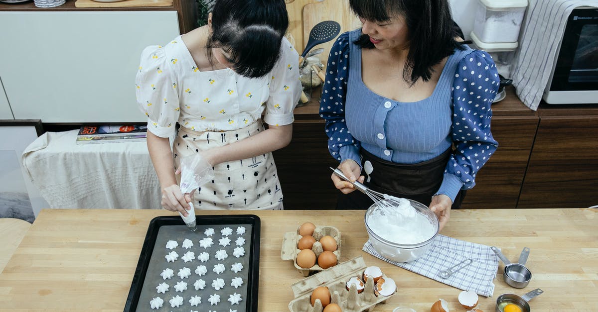 Making my meringues form peaks - From above content Asian housewives wearing stylish outfits and aprons using piping bag to form meringue cookies on baking pan in modern kitchen Making my meringues form peaks - From above content Asian housewives wearing stylish outfits and aprons using piping bag to form meringue cookies on baking pan in modern kitchen