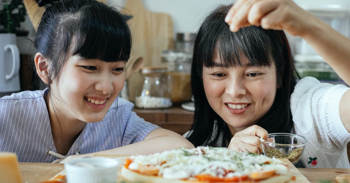 Making Souk. When do I add these Moroccan spices? - Smiling ethnic women adding condiments on pizza Making Souk. When do I add these Moroccan spices? - Smiling ethnic women adding condiments on pizza