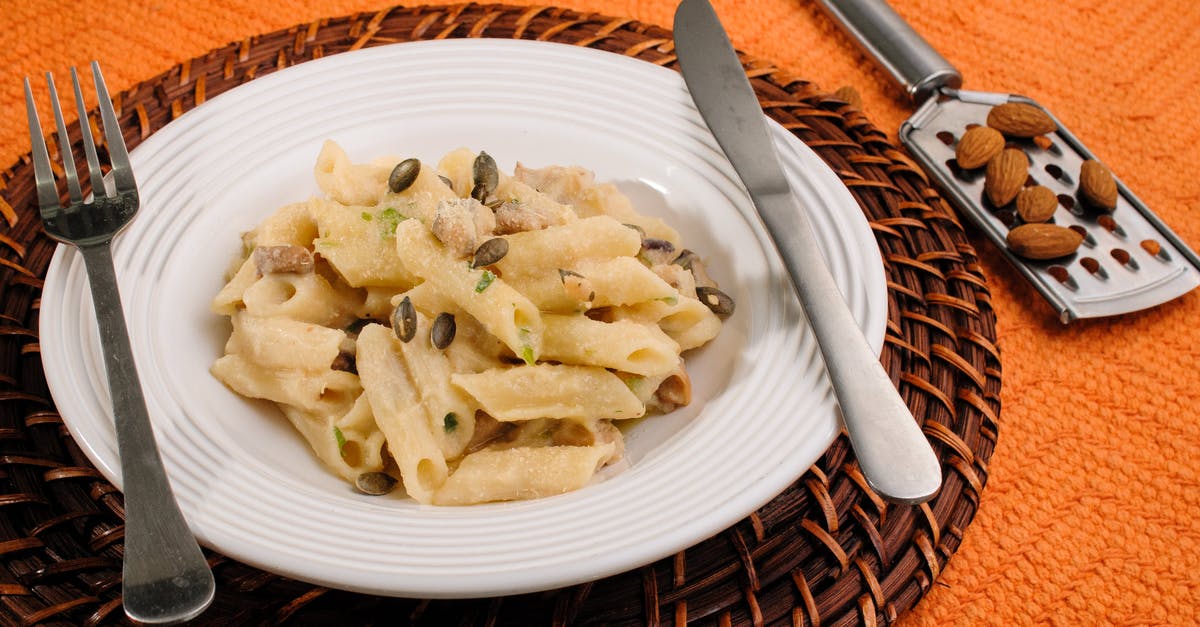Mascarpone and Almond pasta Sauce? - High angle of tasty homemade pasta under cheese and sunflower seeds in plate with fork and knife near heap of almonds Mascarpone and Almond pasta Sauce? - High angle of tasty homemade pasta under cheese and sunflower seeds in plate with fork and knife near heap of almonds