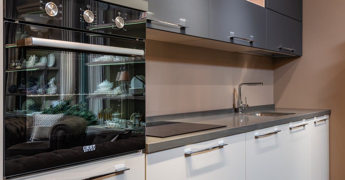 Measuring Oven Temperature: Surface or Air? - Modern black oven placed on counter with stove and sink in light stylish kitchen with white and gray cupboards in apartment Measuring Oven Temperature: Surface or Air? - Modern black oven placed on counter with stove and sink in light stylish kitchen with white and gray cupboards in apartment