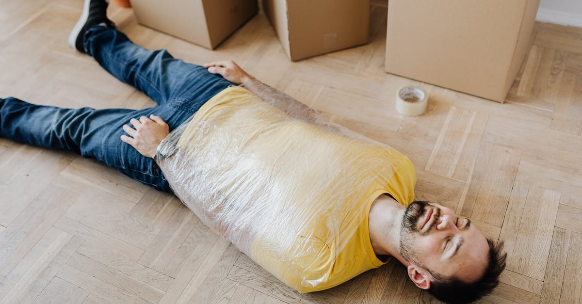 Melted plastic wrap in oven at high temp - High angle of tired male in casual wear wrapped in plastic tape and lying on parquet with eyes closed near carton boxes during relocation Melted plastic wrap in oven at high temp - High angle of tired male in casual wear wrapped in plastic tape and lying on parquet with eyes closed near carton boxes during relocation