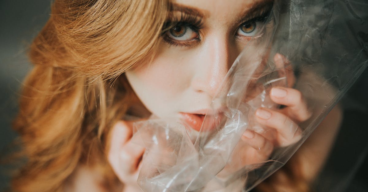 Melted plastic wrap in oven at high temp - From above of young female with blond hair looking at camera with transparent polythene package near face in light room Melted plastic wrap in oven at high temp - From above of young female with blond hair looking at camera with transparent polythene package near face in light room