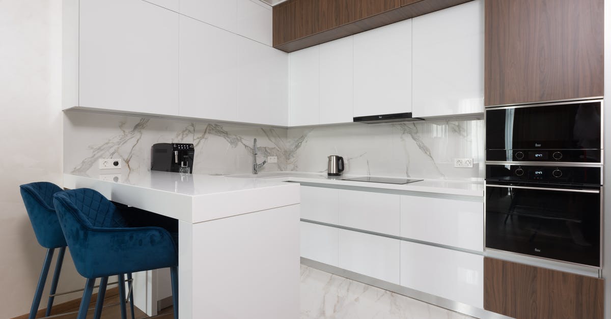 Microwave rice cooker vs low-end electric rice cookers - Interior of light modern kitchen with chairs at dining table and appliances placed in modern apartment Microwave rice cooker vs low-end electric rice cookers - Interior of light modern kitchen with chairs at dining table and appliances placed in modern apartment