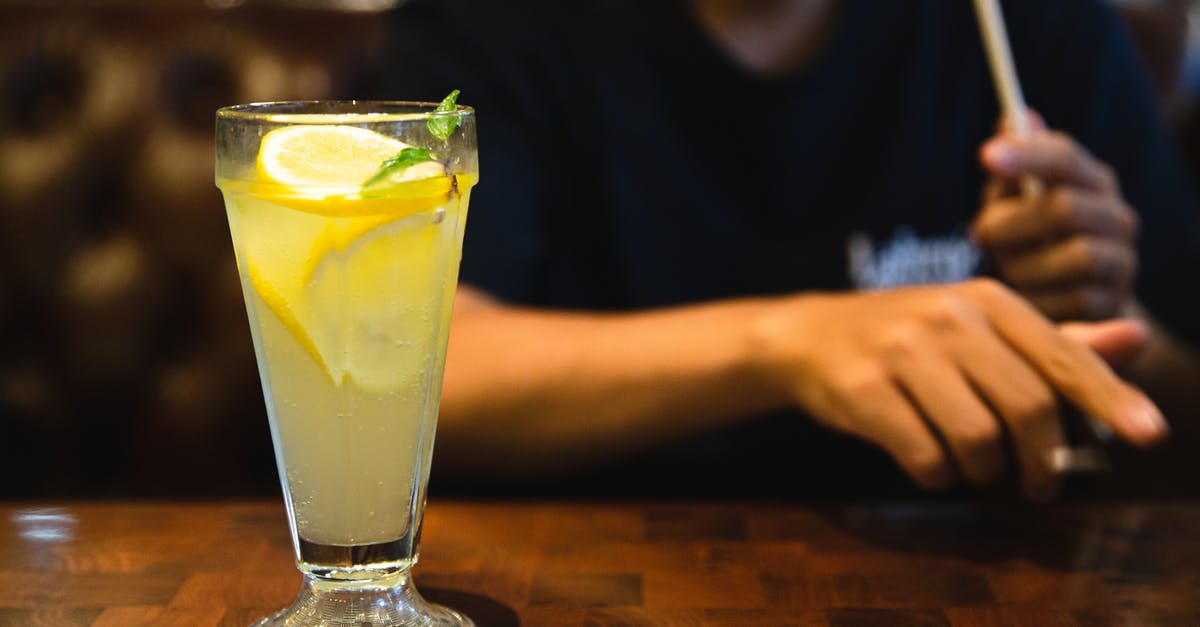Mint vs Peppermint - Crop faceless man sitting at table with fresh citrus lemonade Mint vs Peppermint - Crop faceless man sitting at table with fresh citrus lemonade
