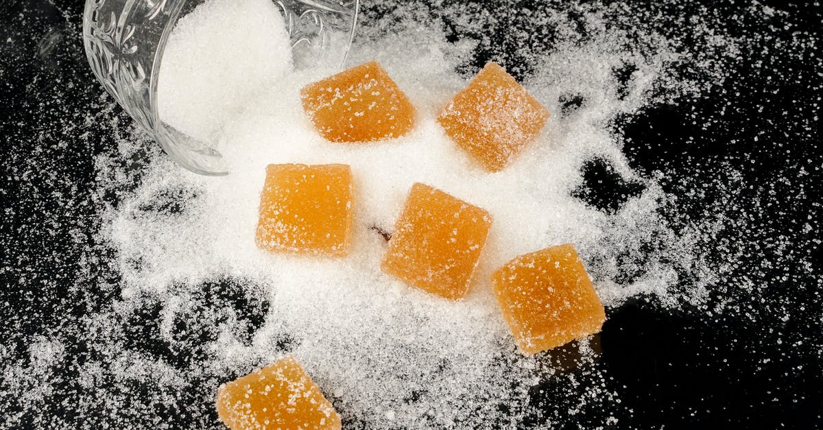 Mixing starches with sugar to make chewy candies - Sugar Coated Yellow Square Candies on a Black Surface with Sugar Mixing starches with sugar to make chewy candies - Sugar Coated Yellow Square Candies on a Black Surface with Sugar