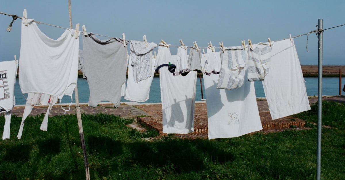 Molasses - dry vs. wet - Drying washed laundry hanging on clothesline between poles on grassy seashore on sunny summer weather Molasses - dry vs. wet - Drying washed laundry hanging on clothesline between poles on grassy seashore on sunny summer weather
