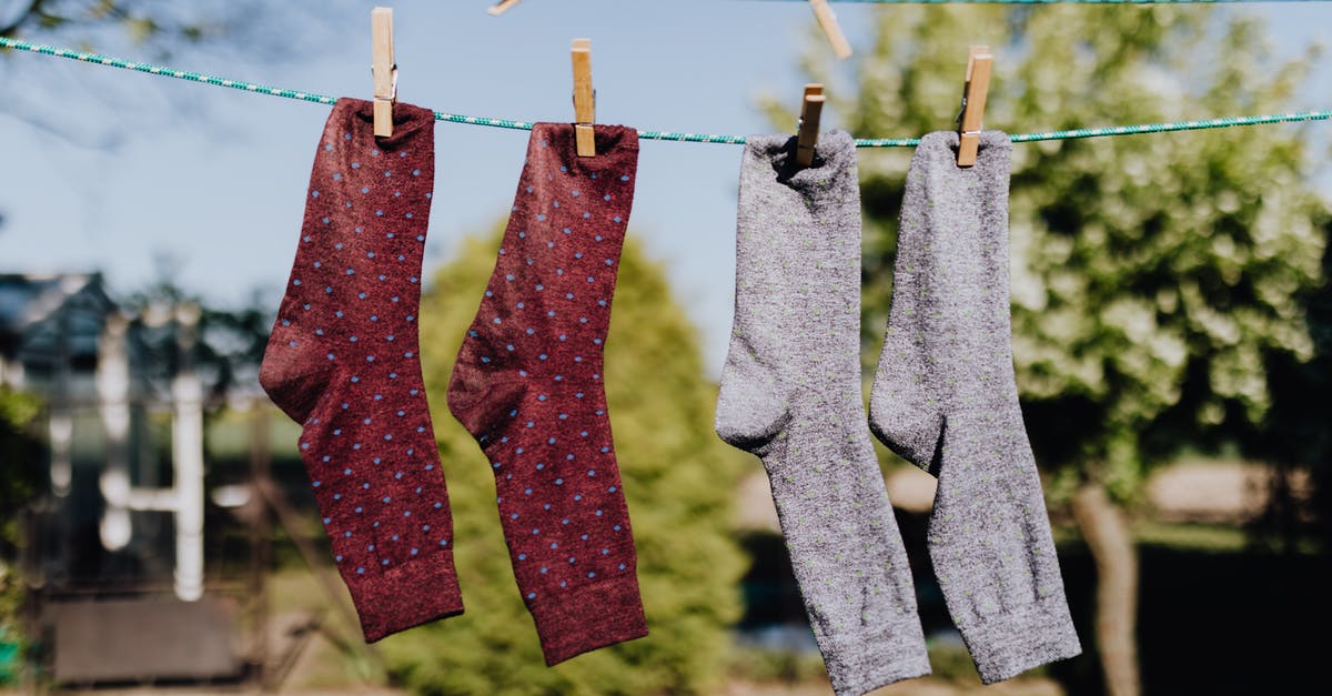 Molasses - dry vs. wet - Soft focus of washed multicolored socks hanging on rope with clothespins outdoors on sunny summer day against natural background Molasses - dry vs. wet - Soft focus of washed multicolored socks hanging on rope with clothespins outdoors on sunny summer day against natural background