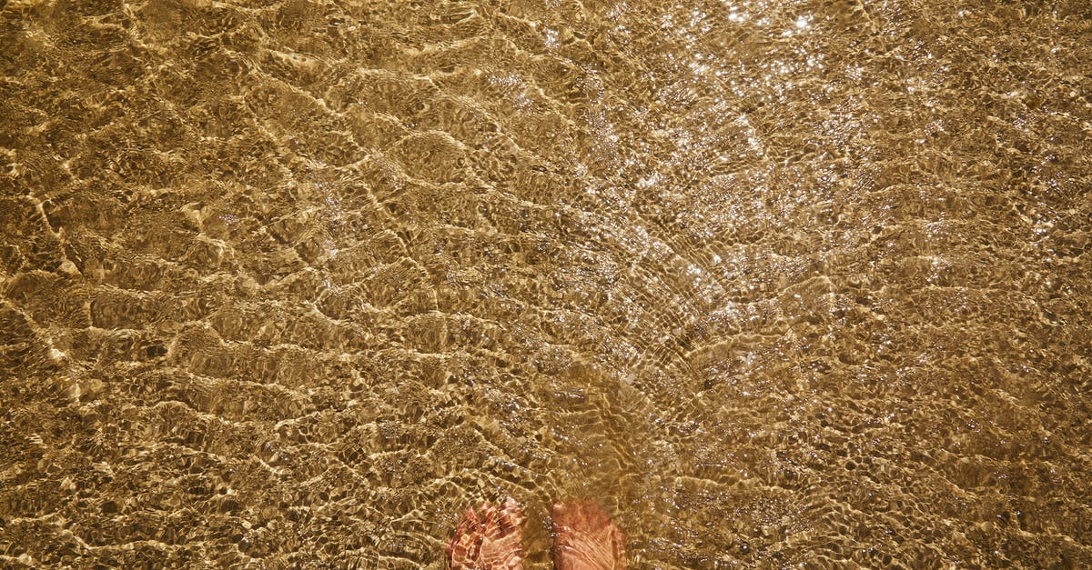 mousse with liquid in bottom - Top view of crop anonymous barefoot female standing in pure transparent rippling water of sea with sandy bottom mousse with liquid in bottom - Top view of crop anonymous barefoot female standing in pure transparent rippling water of sea with sandy bottom